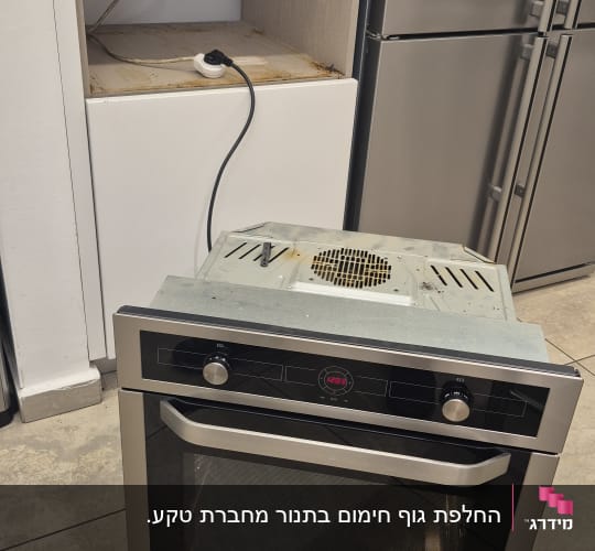 תנור חשמלי מונח על הרצפה ליד שקע חשמלי